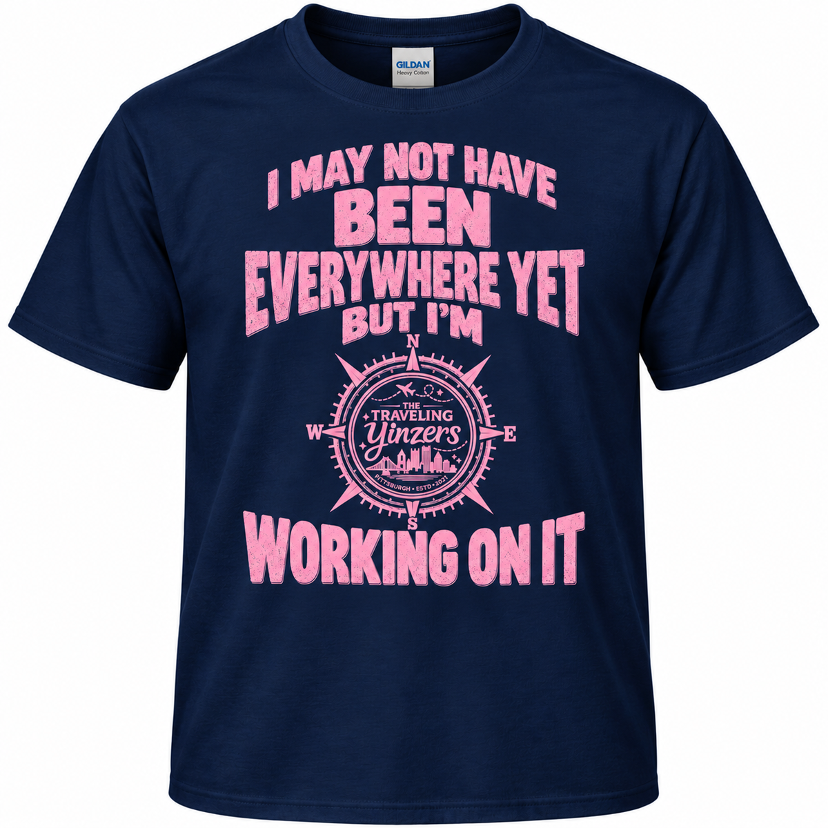 A navy blue short-sleeve t-shirt with a pink graphic text print on the front reading 'I MAY NOT HAVE BEEN EVERYWHERE YET BUT I'M WORKING ON IT' around a compass design.